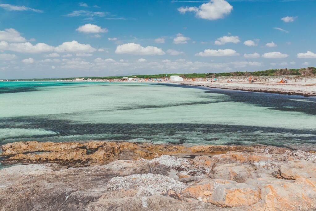 Płytkie turkusowe wody przy kamienistej plaży, idealne kąpieliska Wysp Liparyjskich.