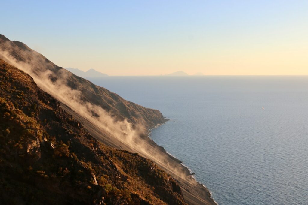Steep volcanic slope shedding dust into sea near the Aeolian Islands at sunset