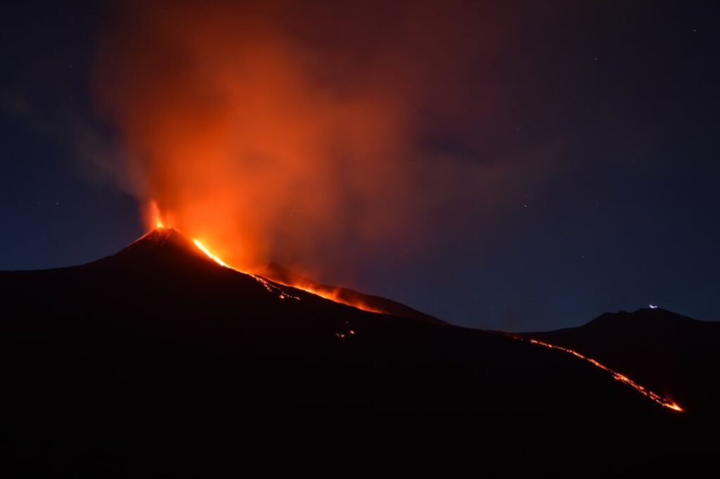 Éruption volcanique nocturne illuminant le ciel et coulées de lave, Îles Éoliennes