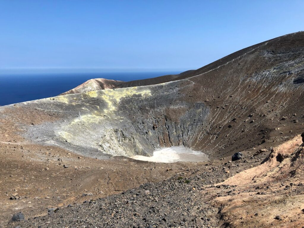 Cratère volcanique désertique aux dépôts jaunes surplombant la mer, Îles Éoliennes