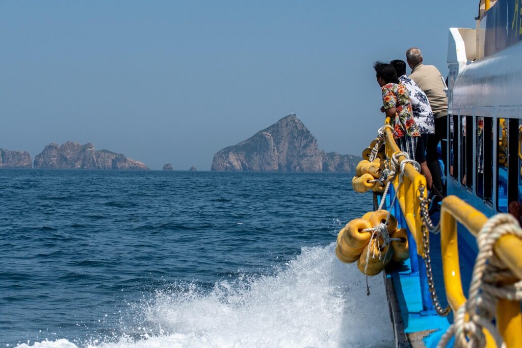 Passeggeri su traghetto guardano gli scogli e le Isole Eolie all'orizzonte