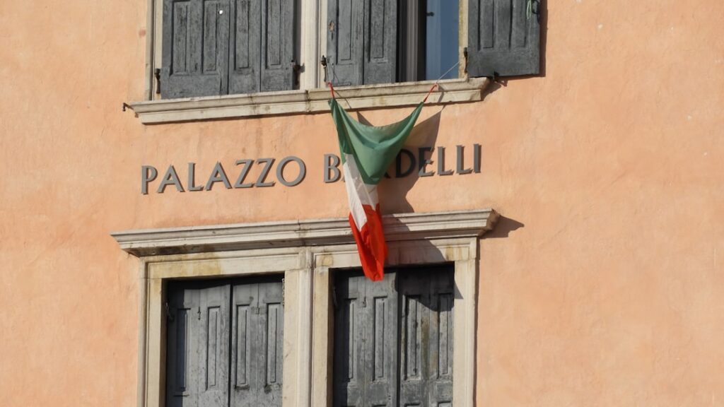 Façade ocre avec inscription 'PALAZZO' et drapeau italien à Gênes