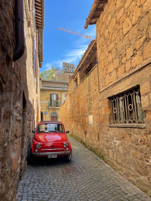 Czerwony Fiat 500 zaparkowany w wąskiej brukowanej uliczce Genui