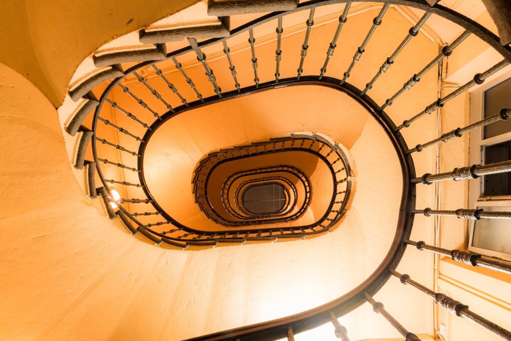 Escalier en colimaçon ocre vu de dessous dans un palais de Gênes