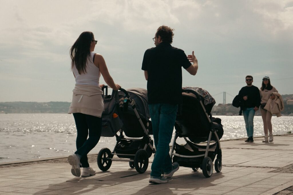 Ouders duwen twee kinderwagens langs waterkant op promenade in Ravenna