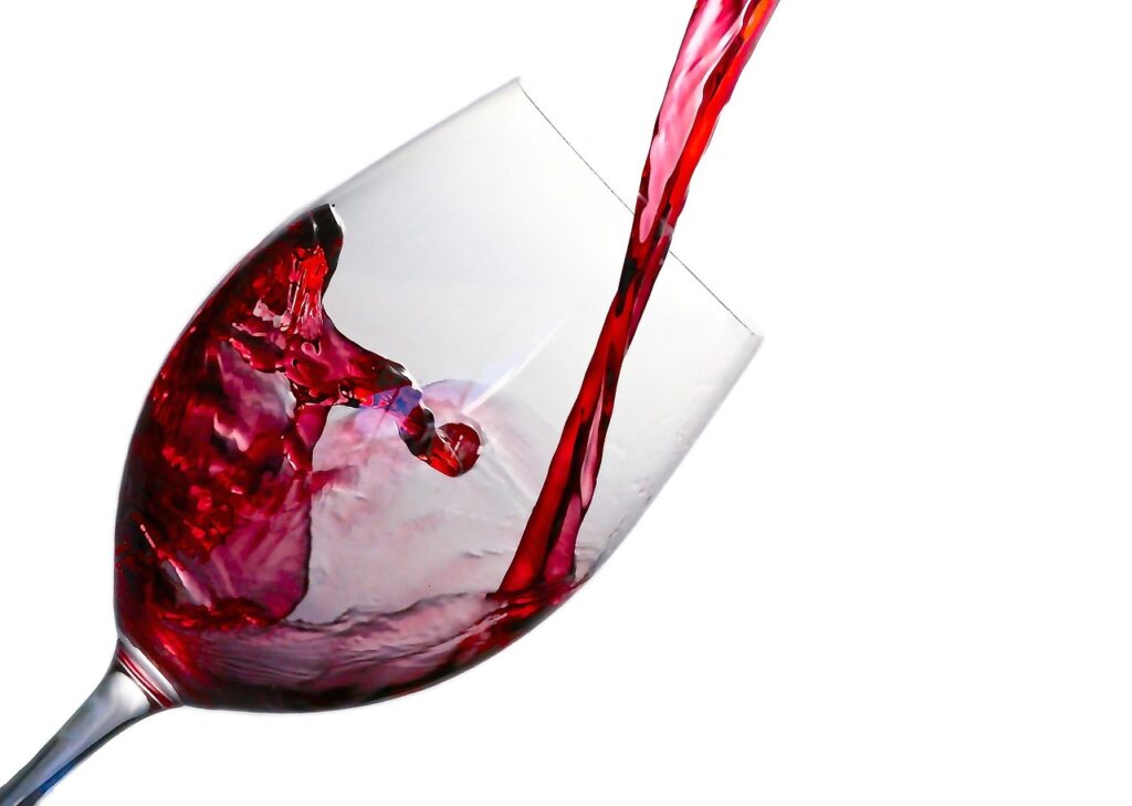 Verre de vin rouge versé sur fond blanc, éclaboussure visible