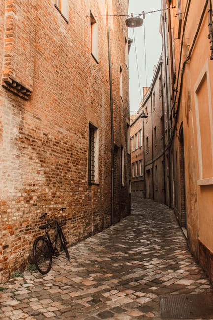 Ruelle pavée avec vélo appuyé contre un mur de briques à Ravenne