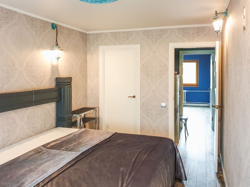 Gemütliches Schlafzimmer mit grauem Bett und Blick ins blaue Nebenzimmer in Ravenna