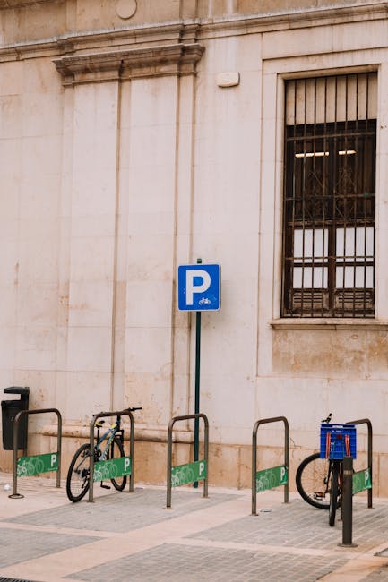 Stojaki rowerowe przy kamiennej ścianie i znaku parkingu w Modenie