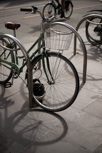 Vélo vert garé à un arceau, panier avant, ombre au sol à Modène