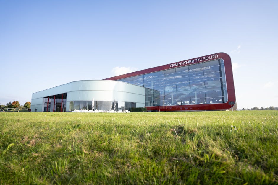 Bâtiment moderne à façade vitrée rouge sur pelouse dégagée