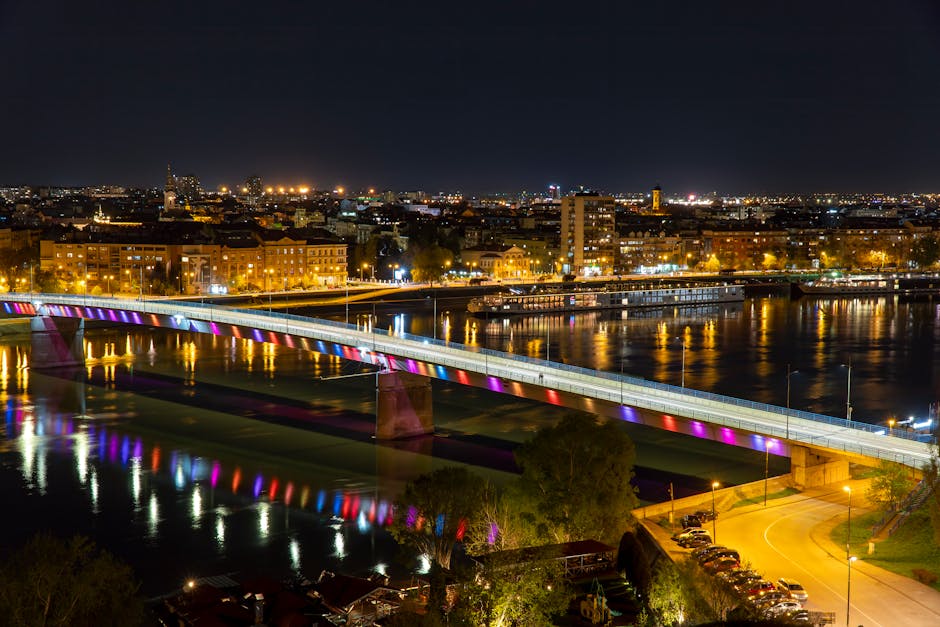 Most o kolorowym podświetleniu odbijający się w nocnej tafli rzeki