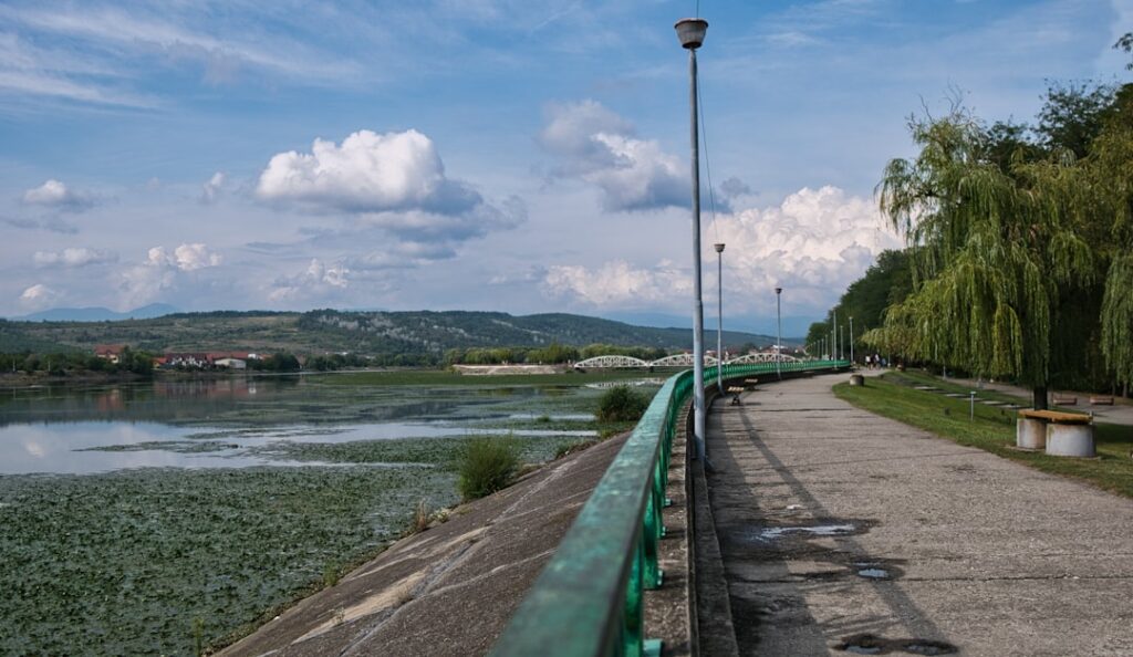 Promenade bord de l'eau à Modène avec rambarde verte et peu de monde