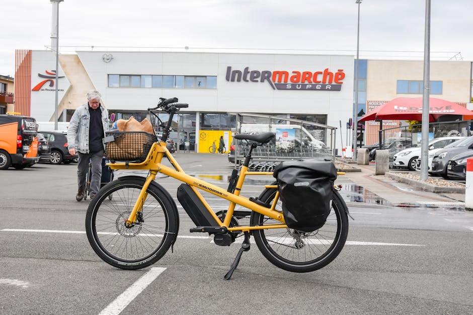 Cargo-bike gialla con cesto parcheggiata davanti a supermercato Intermarché
