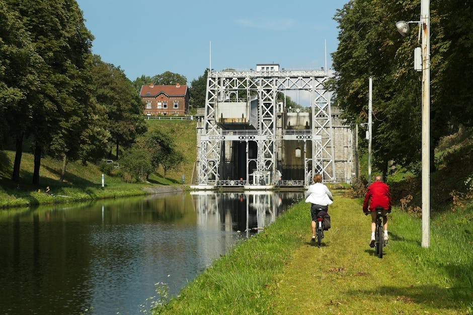 Two cyclists pedaling beside a calm canal near Modena lock