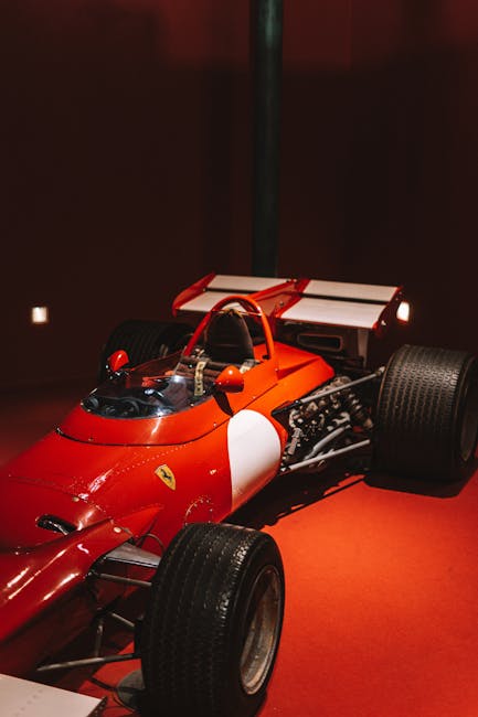 Ancienne monoplace Ferrari rouge exposée sur fond rouge dans musée de Modène