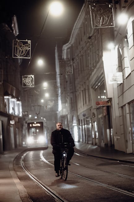 Man cycling on tram tracks at night in Modena street