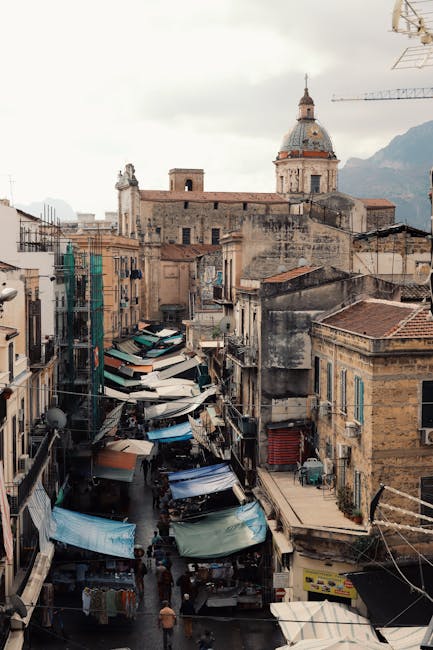 Bancarelle affollate lungo una strada storica con cupola sullo sfondo