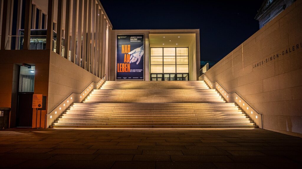 Illuminated steps leading to James-Simon-Galerie entrance under night sky.