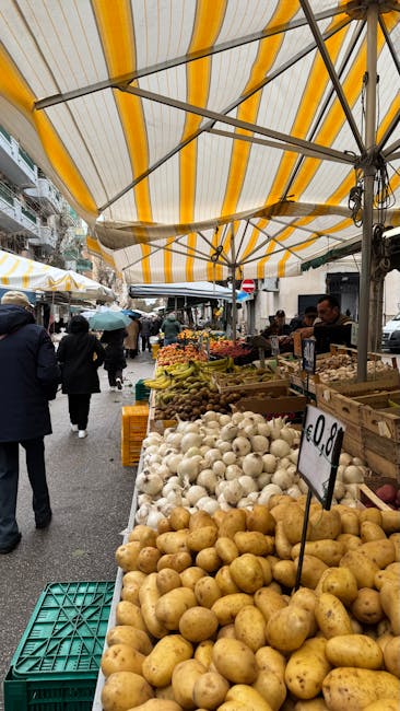 Banchi di ortofrutta sotto tende a righe al mercato di Modena