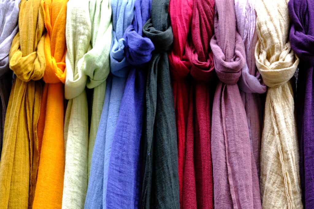 Rij felgekleurde sjaals aan haken op een markt in Modena