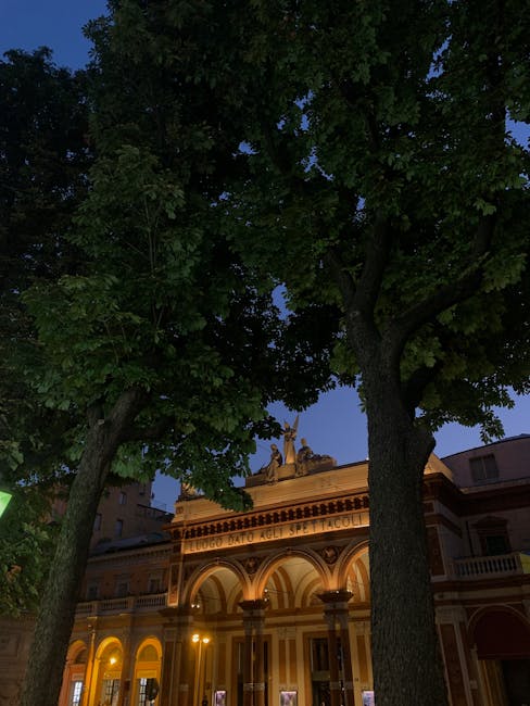 Verlichte gevel van historisch theater in Modena, bomen op voorgrond
