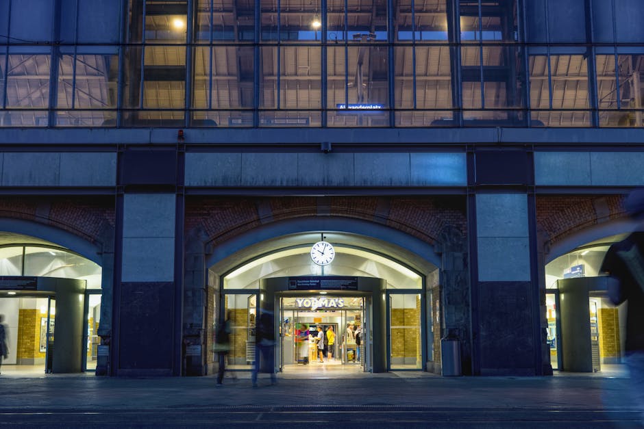 Arched station entrance with illuminated clock above busy doorway at night