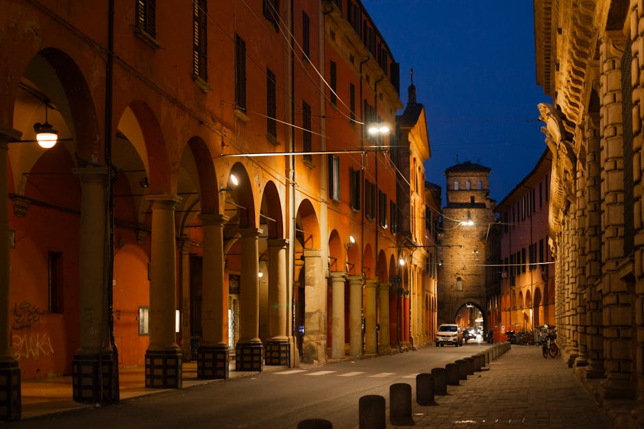 Portici notturni di Modena illuminati con torre visibile sullo sfondo