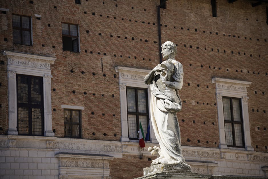 Statue en marbre devant façade en brique, drapeau italien à Modène