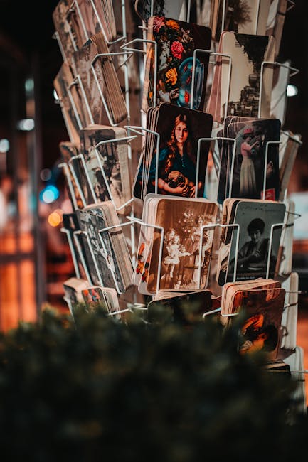 Rotating souvenir rack filled with vintage-style art postcards at night.