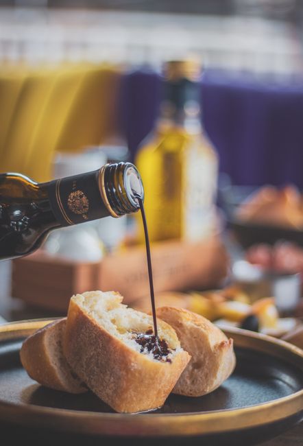 Versare aceto balsamico invecchiato su formaggio durante una degustazione