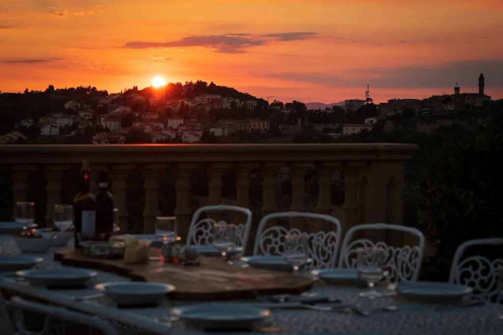 Terrace dining set with empty plates facing a fiery sunset.