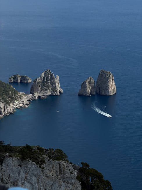 Faraglioni di Capri con mare blu e scia di una barca