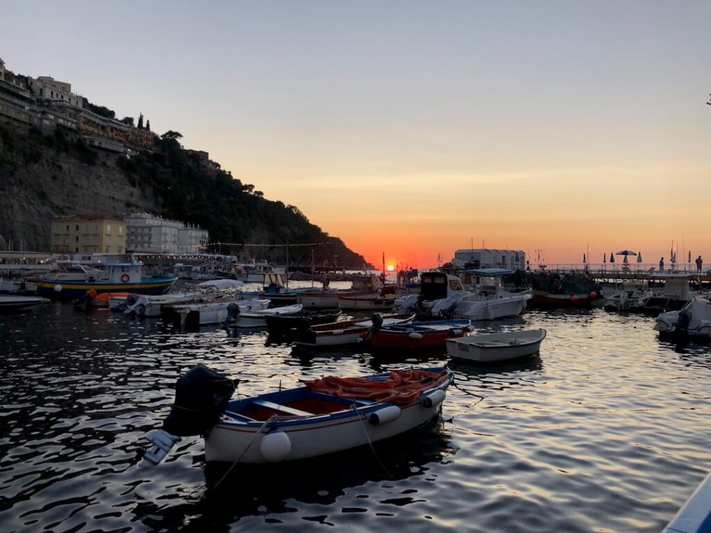 Vissersboten in Capri-haven bij zonsondergang met reflecties op water