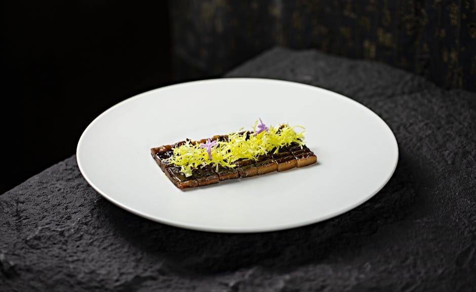 Minimalist gourmet dish: rectangular tart topped with frisée and flowers.