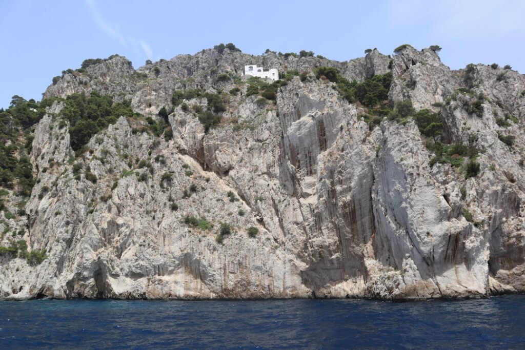 Maison blanche isolée perchée sur une falaise rocheuse à Capri