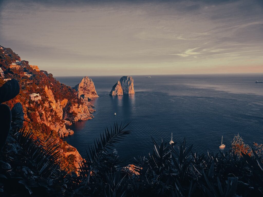 Cliffs and Faraglioni rocks off Capri coastline at sunset