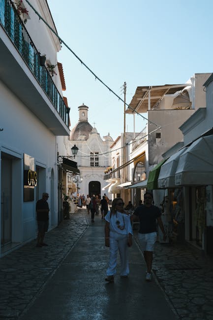 Belebte Gasse in Capri mit weißen Gebäuden und vorbeigehenden Menschen