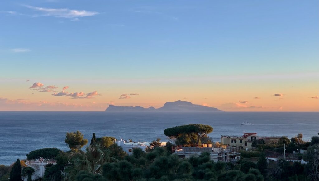 Tramonto su Capri con luce dorata sui Faraglioni e terrazze delle ville