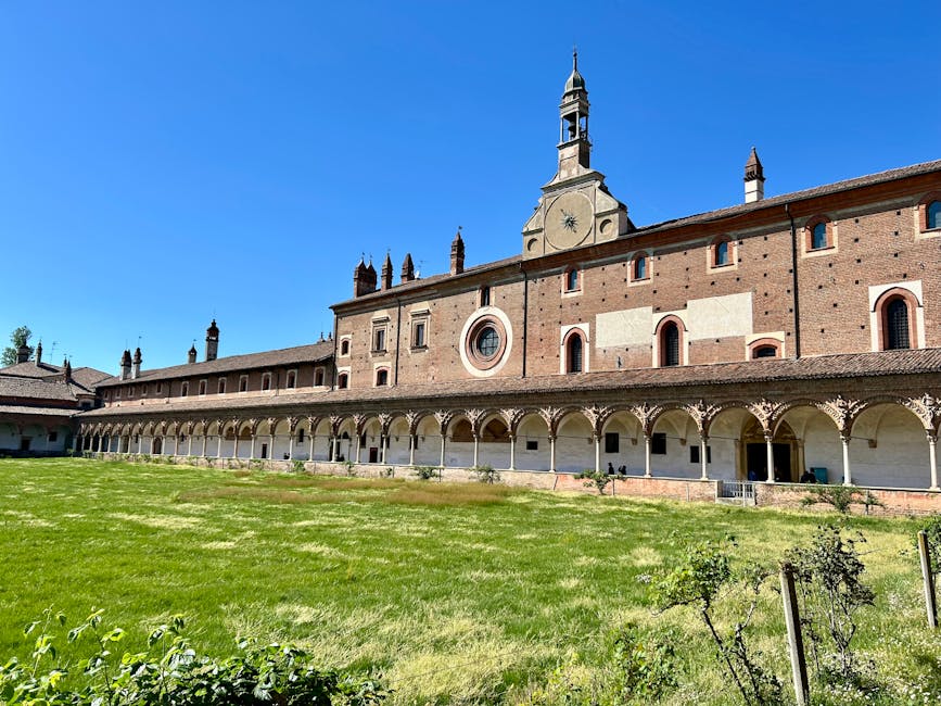 Long cloître à arcades et façade en brique sous ciel bleu