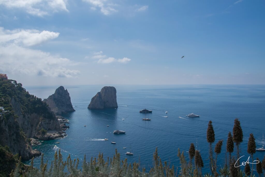 Falaises et Faraglioni de Capri entourés de yachts et petites embarcations