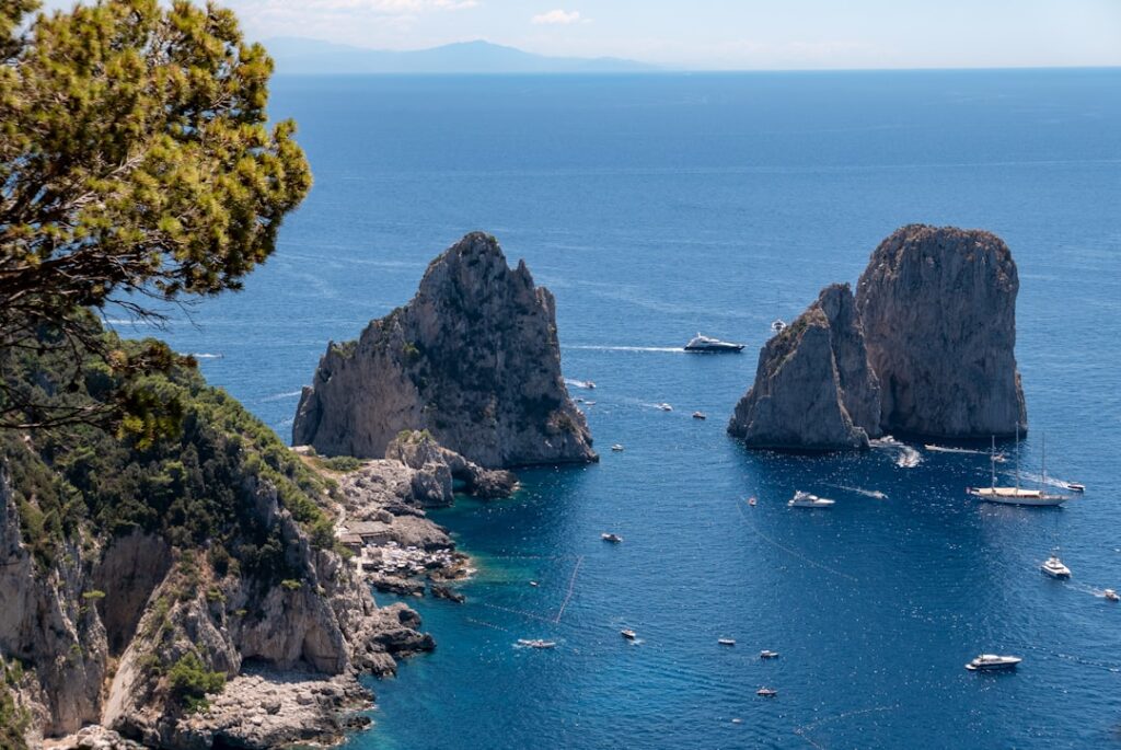 Boats circling the Faraglioni rock formations off Capri on a sunny day