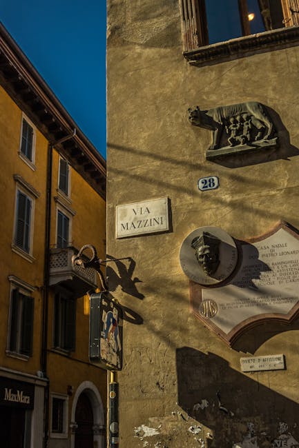 Hausfassade mit Straßenschild 'Via Mazzini' und antiken Reliefs