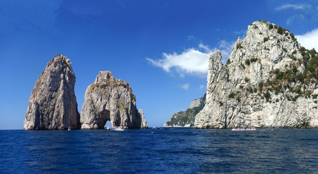 Three Faraglioni rock stacks rising from blue sea near Capri