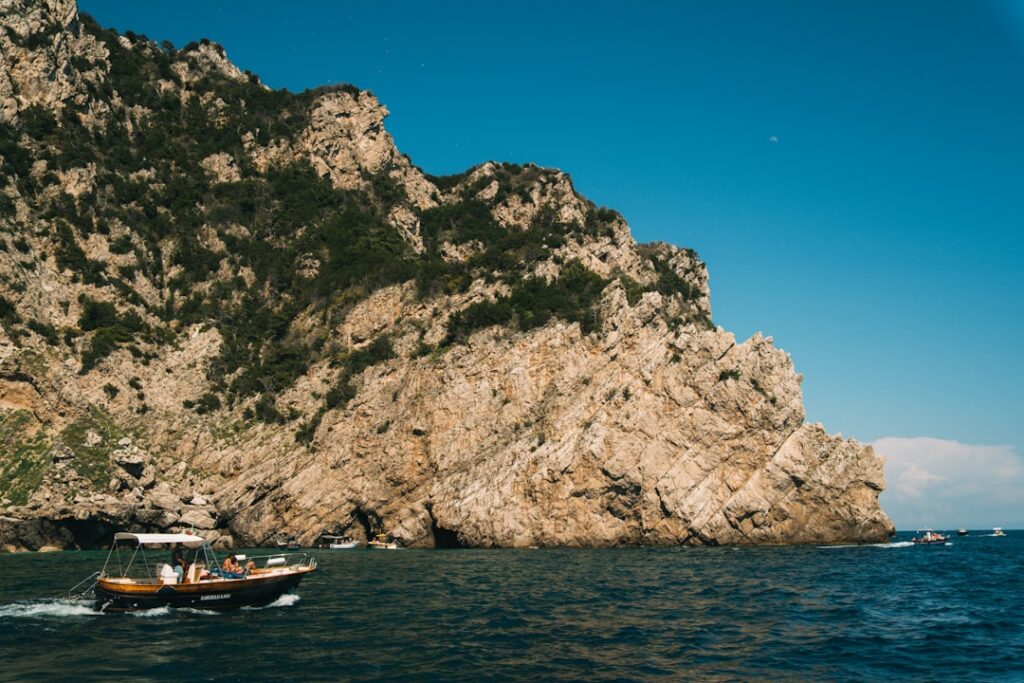 Rotsachtige kust van Capri met bootjes op het diepe blauwe water
