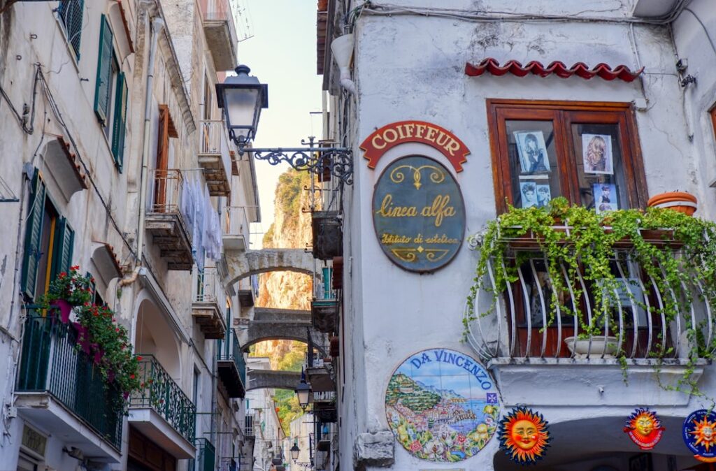 Ruelle caprese aux façades décorées, enseigne 'Coiffeur' et arcades