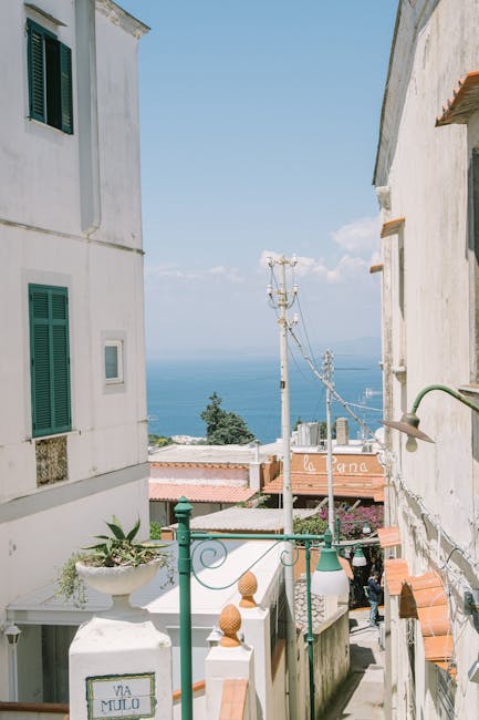 Smal steegje op Capri met groene luiken en uitzicht op zee