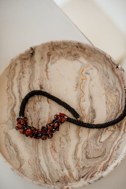 Collier artisanal caprese en perles et corail posé dans bol marbré