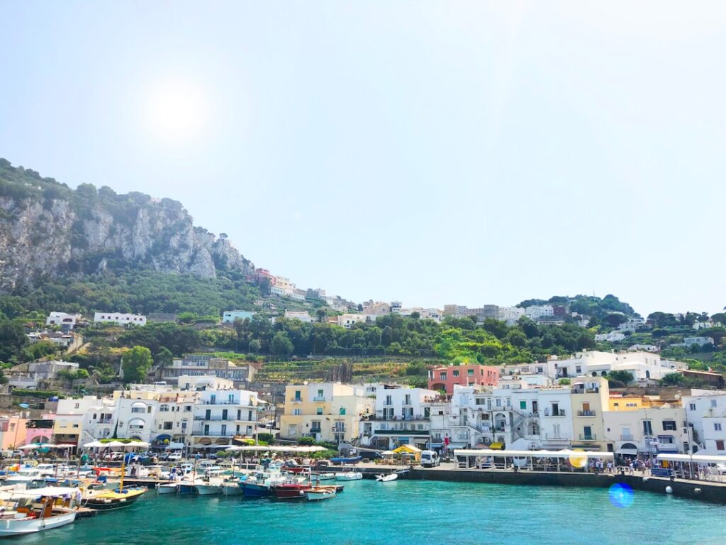 Colorful boats moored at Capri harbor with hillside houses and cliffs