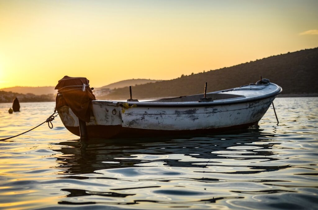 Small moored boat bobbing on golden sunset water near Capri